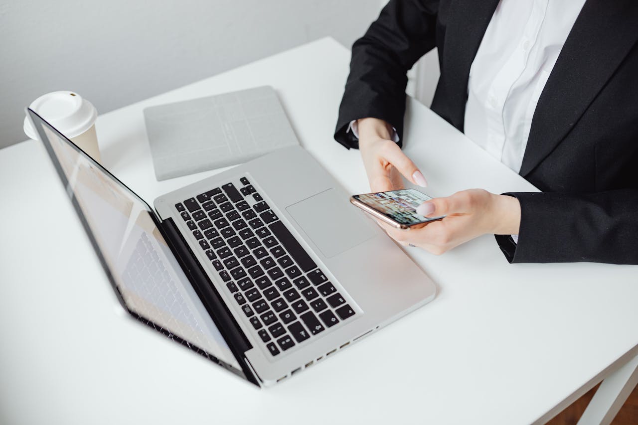 home-hero Businesswoman using smartphone at desk with laptop and coffee cup.